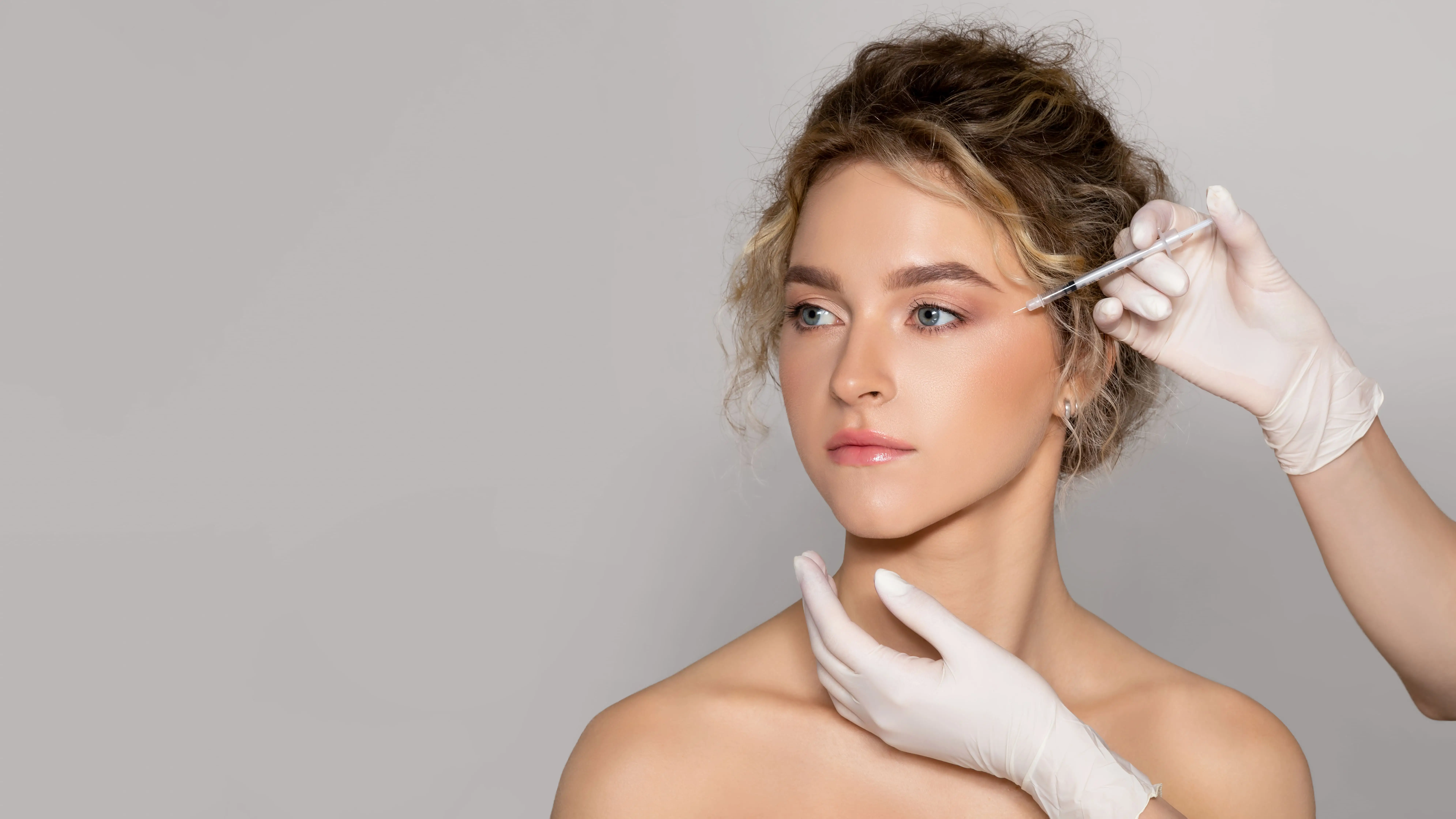young-beautiful-woman-getting-botox-injection-eyes-area-standing-grey-background-panorama-copy-space-1-1