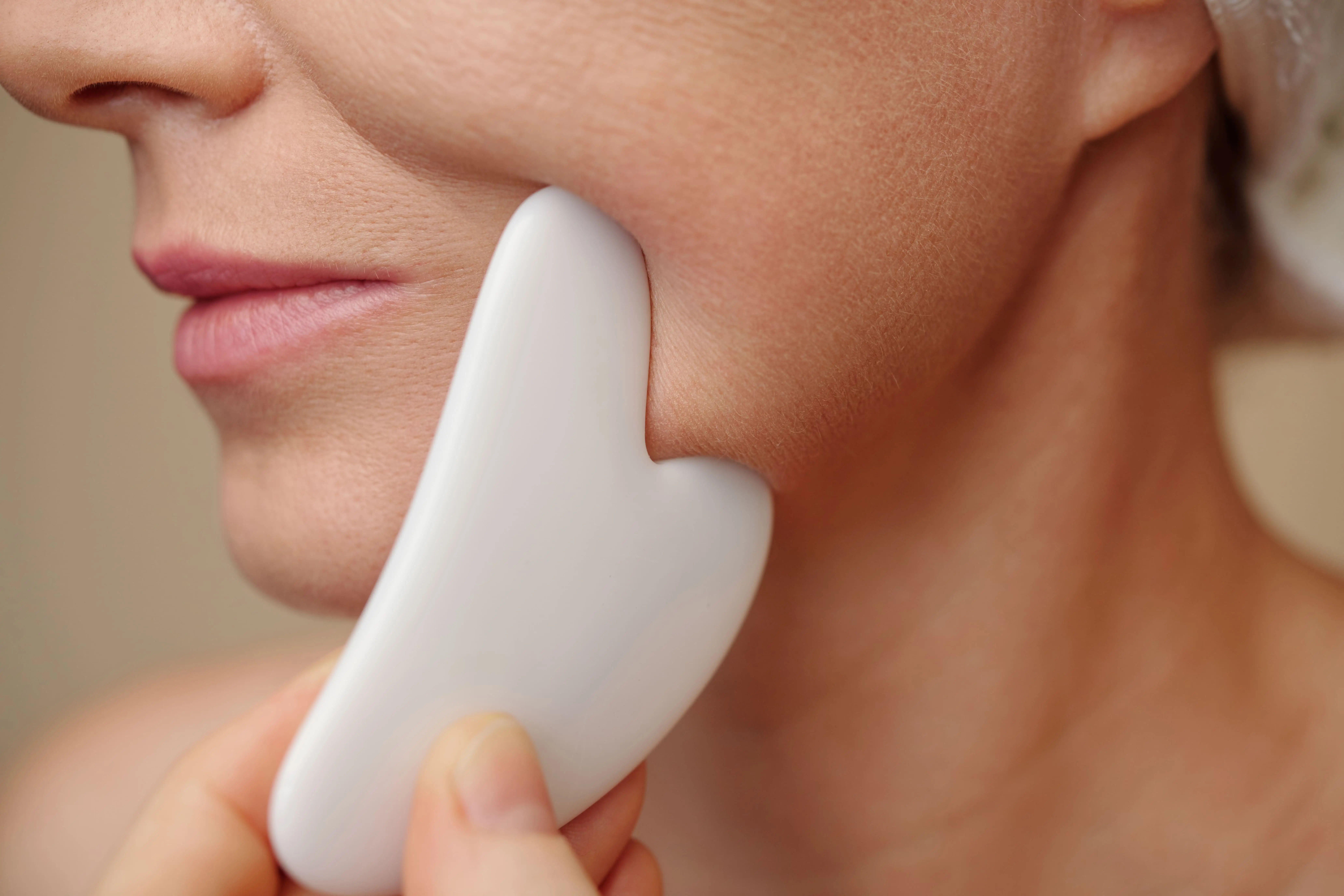 femme se massant le visage avec le gua sha