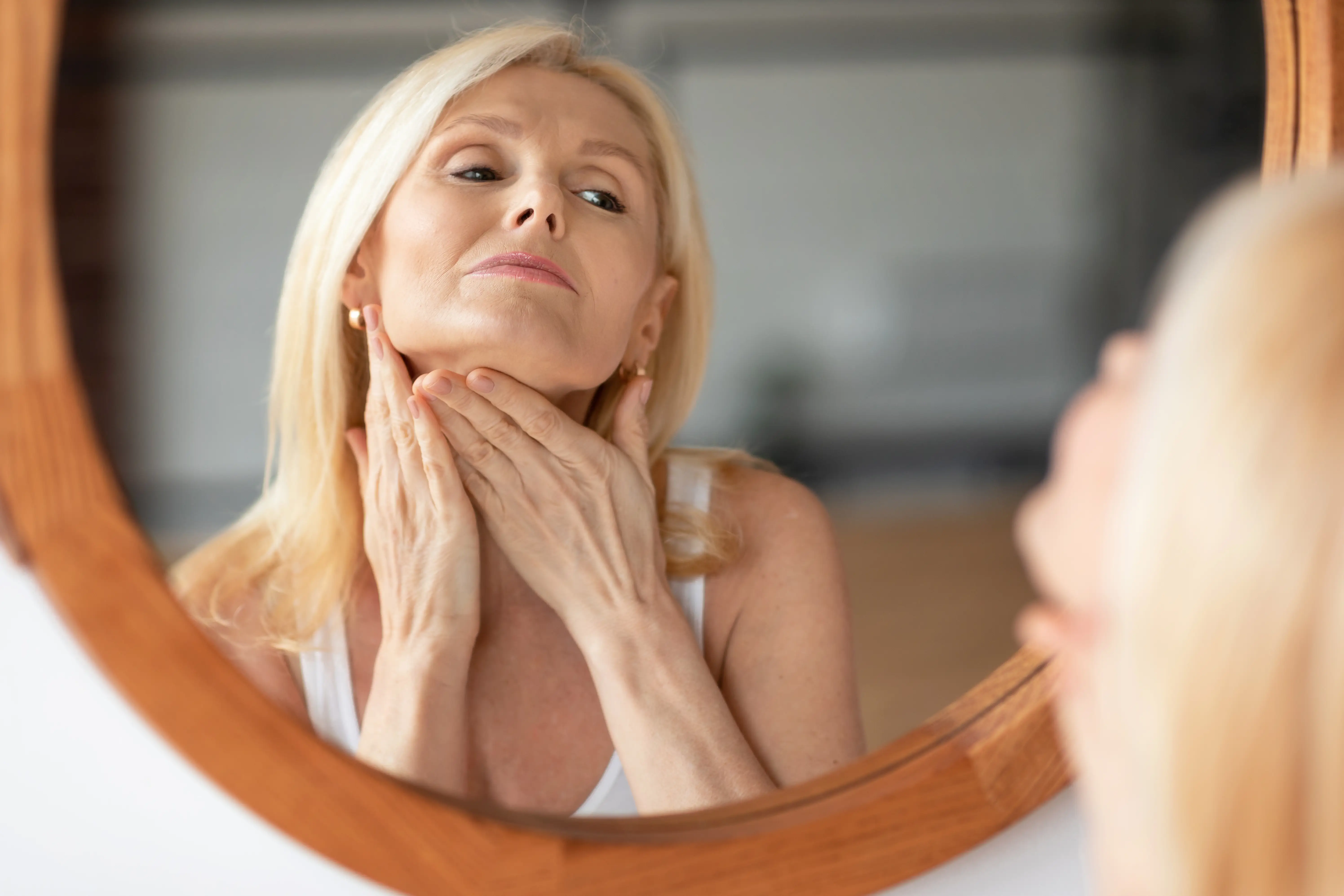 double-chin-treatment-middle-aged-woman-touching-soft-skin-neck-looking-mirror-enjoying
